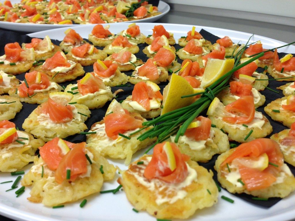 Oval platter with small salmon blini canapes garnished with lemon